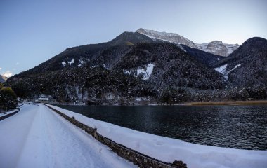Taze kar yağışlı güzel bir kış manzarası. Köknar ağaçları, mavi gökyüzü, güneş ışığı ve yüksek dağlarla kaplı arka plan ağaçlarla kaplı güzel kış manzarası.