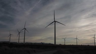 Rüzgar türbinleri şafak vakti mavi gökyüzünde, rüzgar tarlaları yeşil enerji üretiyor. Rüzgar türbinleri güneşli bir günde mavi gökyüzüne karşı dönüyor. Yenilenebilir enerjili enerji üretimi. 