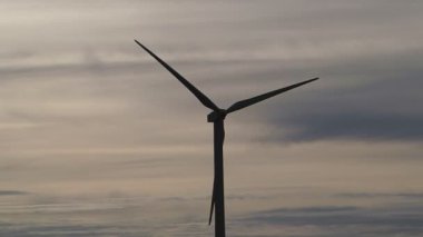 Rüzgar türbinleri şafak vakti mavi gökyüzünde, rüzgar tarlaları yeşil enerji üretiyor. Rüzgar türbinleri güneşli bir günde mavi gökyüzüne karşı dönüyor. Yenilenebilir enerjili enerji üretimi. 