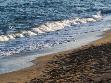 Dalgalar ve deniz kıyısındaki kum köpüğü.