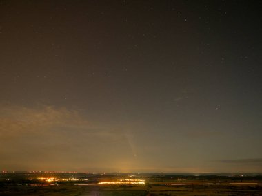 Gece gökyüzünde yıldızlar ve bulutlarla kuyruklu yıldız.