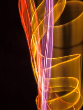 Siyah arkaplanda renkli neon ışık çizgileri. Parlak renklerde dönen soyut ışık yolları. Işık resminin bulanık hareketinin ormanları. Geceleri bulanık ışıklar. Kasıtlı kamera hareketi, ICM sahnesi