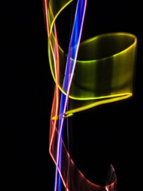 Siyah arkaplanda renkli neon ışık çizgileri. Parlak renklerde dönen soyut ışık yolları. Işık resminin bulanık hareketinin ormanları. Geceleri bulanık ışıklar. Kasıtlı kamera hareketi, ICM sahnesi