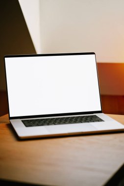 Ahşap masada yeni bir profesyonel laptop var. Uygulama veya web sitesi için tasarım şablonu. Modern evin içinde boş ekranı olan bir defterin maketi. Gümüş alüminyum dizüstü bilgisayar.