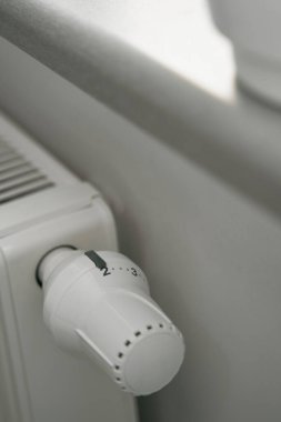Isıtma radyatörünün termostatına yakın çekim. Modern beyaz iç mekanda ısıtıcı regülatörü. Sıcaklık düğmesi
