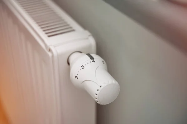 stock image Close-up of turning down the thermostat on a radiator to save energy due to heating cost price hike. Concept of economizing cost during cold weather and energy crisis.
