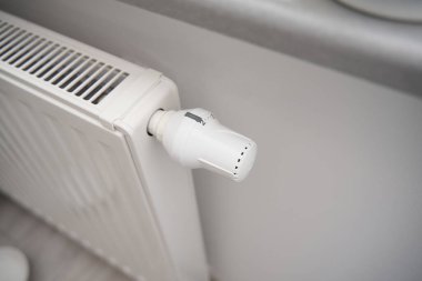 Isıtma maliyeti zammı nedeniyle enerji tasarrufu yapmak için radyatörün termostatını kapatmaya yakın çekim. Soğuk hava ve enerji krizi sırasında maliyetin ekonomik hale getirilmesi kavramı.