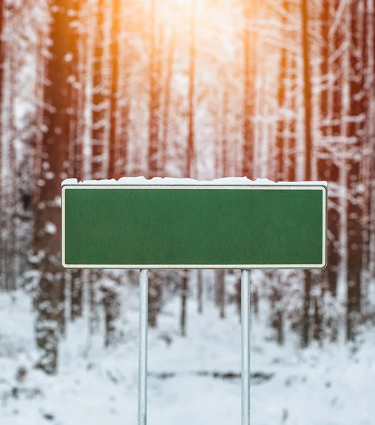 Blank green road sign in winter. Design template for information posts near a highway in winter.
