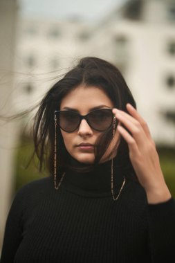 Kendine güvenen ve güzel bir kadın pahalı güneş gözlüğü takar. Kadınlar için lüks aksesuarlar kavramı. Şehirdeki şık esmer kız.