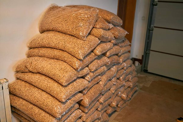 1 тонна деревянных гранул, упакованных в мешки по 15 кг. Деревянные гранулы, сложенные в пластиковые пакеты. Отопительное топливо доставляется в дом для обогрева интерьеров зимой. Концепция устойчивого будущего.