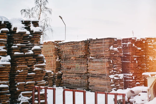 Wooden factory backyard. Storage of wood material on the plant during winter.