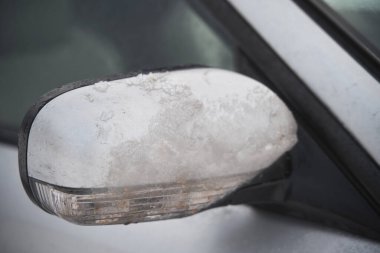 back of the side view mirror covered with ice, snow and frozen water.