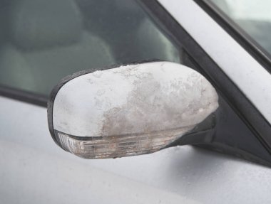 Ice-covered rear view side mirror. Dangerous conditions during winter storm.