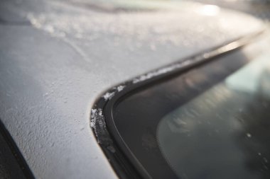 Modern car roof covered with snow on a sunny winter day. The panoramic sunroof in the winter.