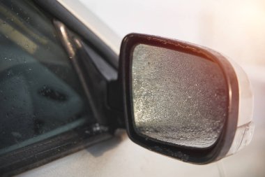 Side view mirror covered with raindrops. Powered car mirror.