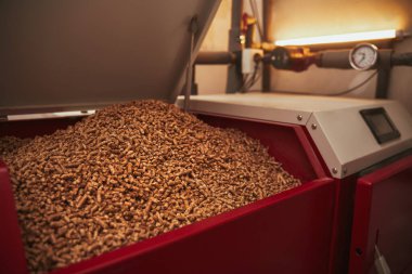 Kazan dairesinde yakıt deposu dolu katı yakıt kazanı. Ahşap pelet ısıtma sobası. Yenilenebilir biyo-enerji ısıtma.