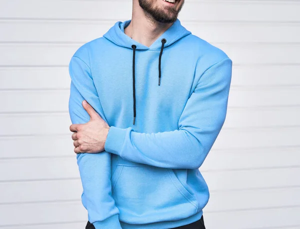 Bearded man standing in light blue hoodie. Azure sweatshirt without a logo. Design mockup of basic wear brand. Logo copy space on clothing.