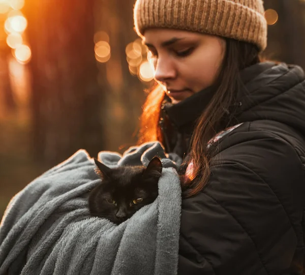 Cat and owner in the park. Caucasian woman holds her cat in the woods