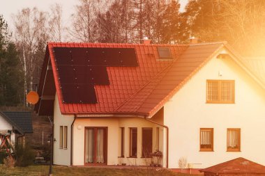 House with a solar panel on the roof. Concept of sustainable resources. Photovoltaics on the red roof of a house. Alternative electricity source.