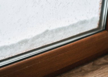 Close up of triple glazed pvc windows during winter. Concept of cozy and warm home during frost weather. Brown window profile.