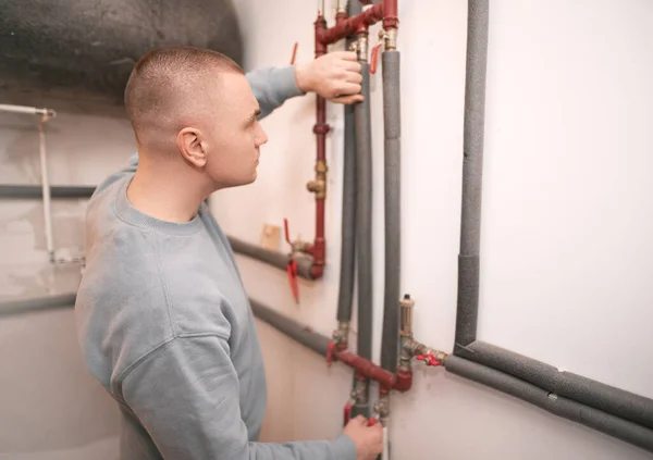 Industrial system engineer shows off his smile while fixing the heating system. Caucasian engineer recommends to use sustainable heating systems.