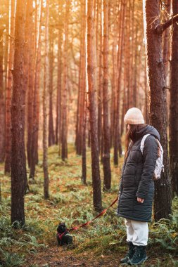 Young girl walking with black cat on a leash in the park