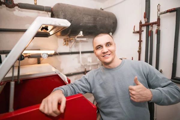 Sustainable future heating. Man using pellet heating oven. Worker portrait in the boiler room.