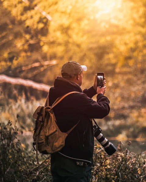 Seorang Pria Mengambil Foto Dengan Ponselnya Sambil Membawa Kameranya — Stok Foto