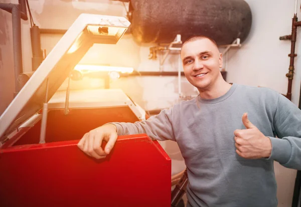 Industrial system engineer shows off his smile while fixing the heating system. Caucasian engineer recommends to use sustainable heating systems
