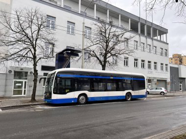 26.02.2023 Gdynia, Trojmiasto, Polonya, Avrupa. Duraktaki mavi elektrikli otobüs pantografla şarj ediliyor