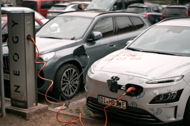 12.04.2023 İtalya, Avrupa. Avrupa 'da bir park şarj istasyonunda elektrikli araba şarj etmek. Yanan iki araba. Sürdürülebilir gelecek kavramı.