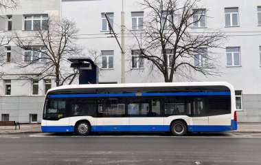 26.02.2023 Gdynia, Trojmiasto, Polonya, Avrupa. Duraktaki mavi elektrikli otobüs pantografla şarj ediliyor