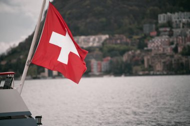 İsviçre bayrağı Lugano Gölü 'nde turistik bir teknede sallanıyor. Üzerinde beyaz haç olan kırmızı bir bayrak..