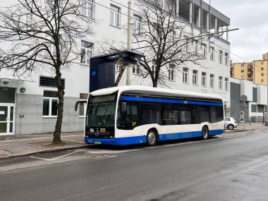 26.02.2023 Gdynia, Trojmiasto, Polonya, Avrupa. Duraktaki mavi elektrikli otobüs pantografla şarj ediliyor