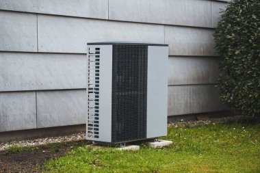 Bahçesinde sıcak su pompası olan beyaz bir ev. Maliyet etkin ısıtma sistemi kavramı