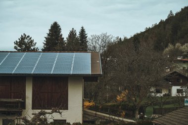 Çatıdaki güneş panelleri. Kırsal bölgelerde ve kırsal bölgelerde sürdürülebilir bir gelecek için fotovoltaik kullanma kavramı. Alternatif elektrik kaynağı olan modern bir ev..
