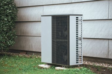 Bahçesinde sıcak su pompası olan beyaz bir ev. Maliyet etkin ısıtma sistemi kavramı