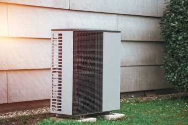 Çimlerin arasındaki evin dışındaki bir havalandırma ünitesi. Modern HVAC ve ısı pompa sistemi