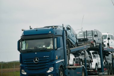 17.04.2023. Avrupa Polonya. Taşıyıcı karavan otoban manzaralı araçlar taşıyor. Otomobil taşımacılığı ve araba nakliye hizmetleri konsepti. Yarı römorklu bir kamyon..