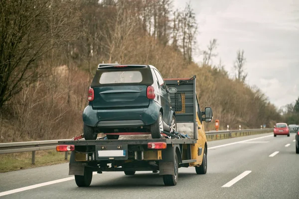 Tow truck with a wrecked car on the highway. Roadside assistance concept.