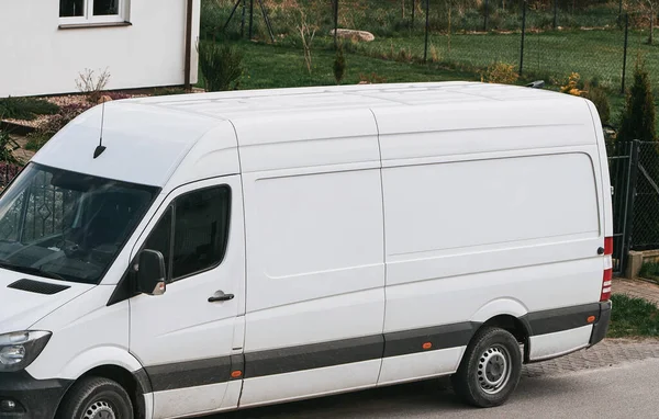 A white delivery van is parked on the side of the road. Door-to-door delivery mockup. Logistics concept.