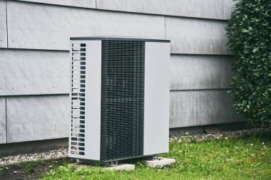 Çimlerin arasındaki evin dışındaki bir havalandırma ünitesi. Modern HVAC ve ısı pompa sistemi