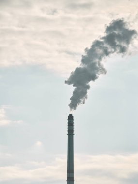 Mavi gökyüzüne karşı bacadan duman çıkıyor.