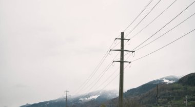 Dağlık vadide yüksek voltajlı elektrik direkleri. Alp manzarasında elektrik direği.