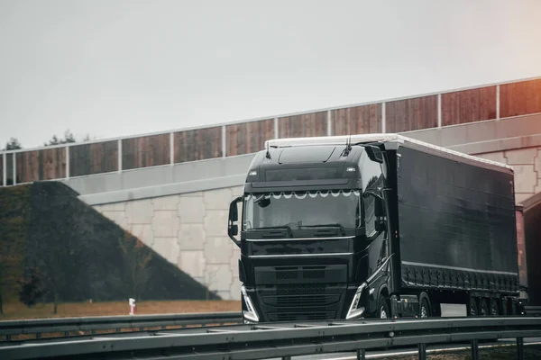 A big truck moves on the highway concept of the shipping company. Landscape with a moving European semi truck
