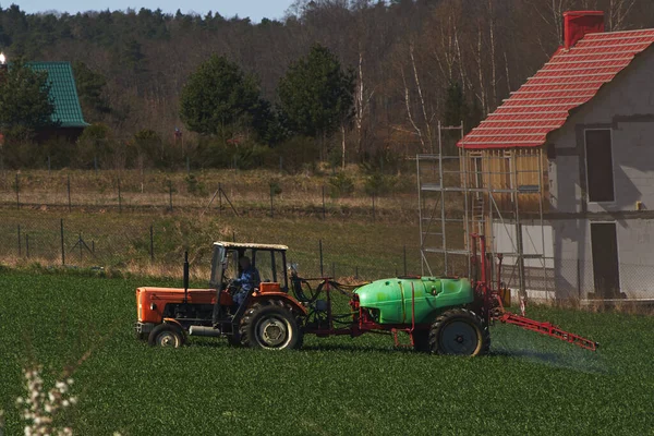 Tractor spraying pesticides on the field with sprayer at spring. agricultural fields in spring. concept of rural farm countryside