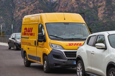 İtalya Avrupa 11.04.2023. Kuzey İtalya 'daki küçük şehirlerden birine park edilmiş DHL minibüsü. Sarı DHL teslimat kamyonunun önü sokağa park edilmiş.