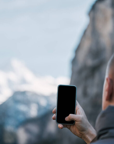 Man taking photos in beautiful outdoors. Traveling in Alps. Camera mockup