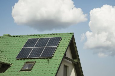 Modern evin çatısındaki güneş panelleri. Çatıda mavi parlak güneş enerjili voltaik panelleri olan bir ev. Yenilenebilir ekolojik yeşil enerji üretim konsepti. Sürdürülebilir.