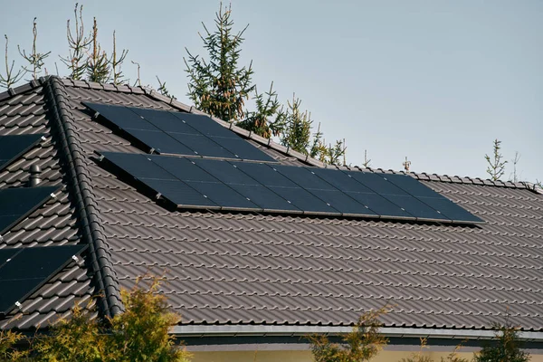 Solar panels on the roof of the modern house. Residential house cottage with blue shiny solar photo voltaic panels system on roof. Renewable ecological green energy production concept. Sustainable.